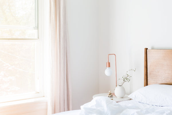 Bright, calm bedroom with white bedding beside an open window
